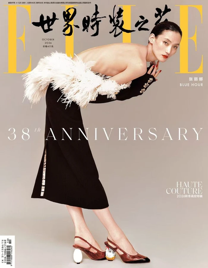 Model Lina Zhang in a black skirt with white feathered trim bending forward against a neutral studio backdrop for Elle China October 2026