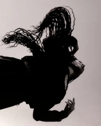 Black woman with long braids mid-motion tossing her hair, wearing dark athletic apparel against a plain light background