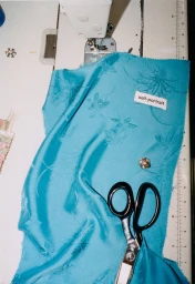 Overhead shot of turquoise floral fabric beneath a sewing machine with scissors and a label.