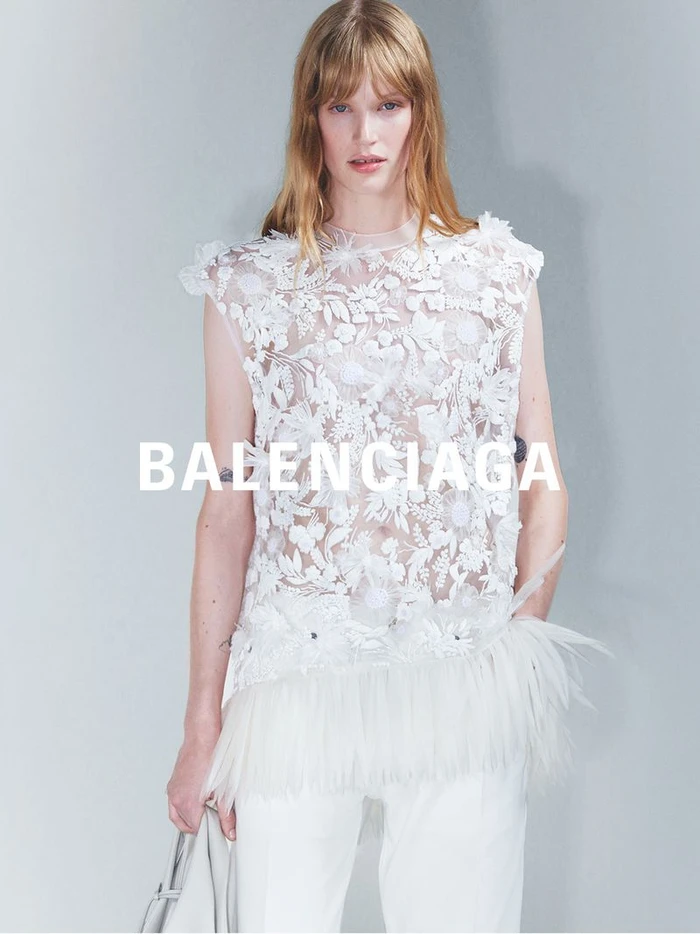 Model in sheer white floral top wearing light trousers against a neutral background for Balenciaga Summer 2027.