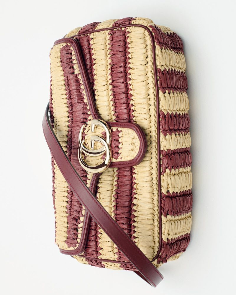 Striped clutch purse, crafted with natural raffia and leather accents, stylish for fashion and accessorizing, set against a white backdrop.