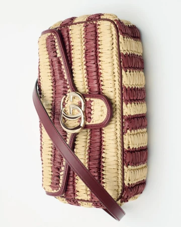 Striped clutch purse, crafted with natural raffia and leather accents, stylish for fashion and accessorizing, set against a white backdrop.