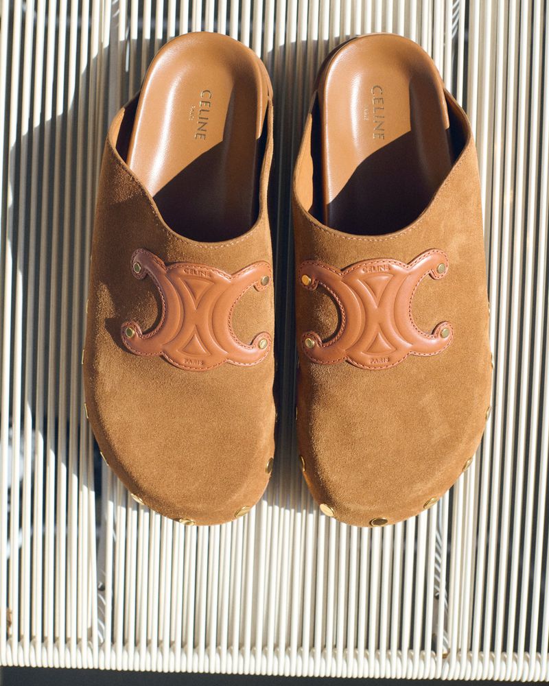 Tan suede Celine mules featuring the brand's Triomphe logo. The photograph showcases the details of the shoes.
