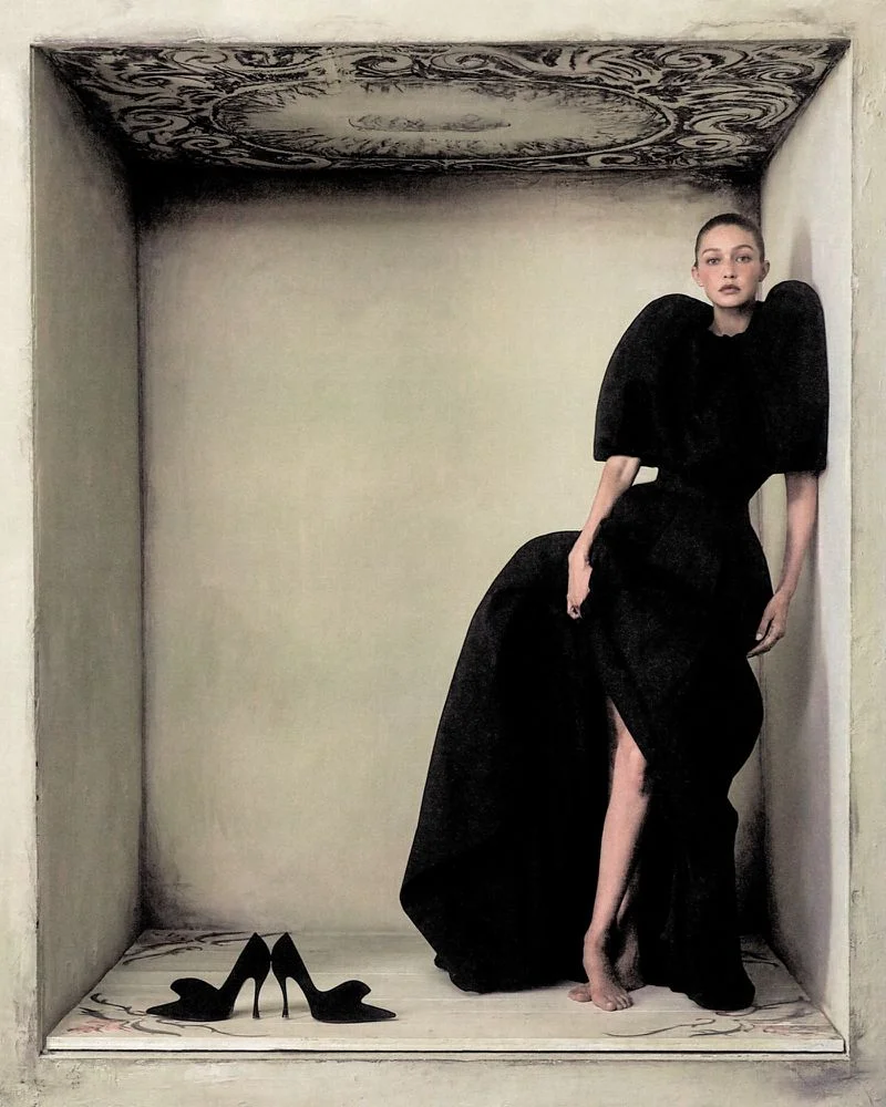 Gigi Hadid posing in a black sculptural dress inside a boxed architectural diorama for WSJ Queen of Couture