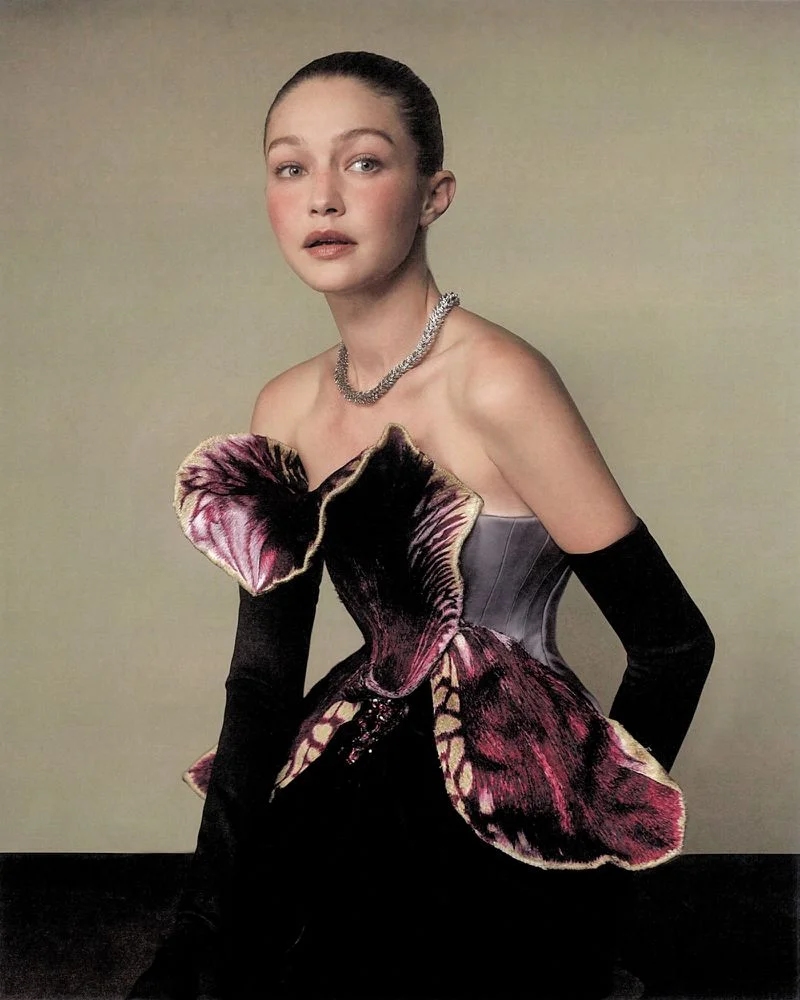 Gigi Hadid in a structured floral bustier top with black opera gloves and a diamond necklace against a neutral background