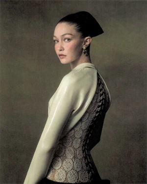 Model Gigi Hadid in a white structured top and dark headpiece against a muted textured background for WSJ Queen of Couture editorial.