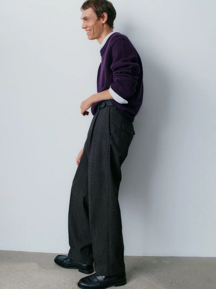 Aleksandr Gordeev in a purple crewneck sweater and charcoal trousers against a neutral background for Arket.