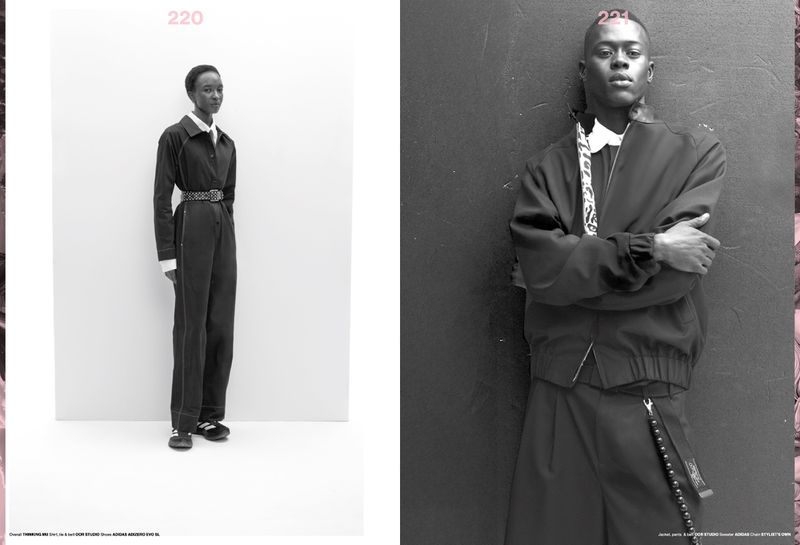 Two young adult fashion models pose in black and white, one in a jumpsuit and the other in a jacket with folded arms against a wall.
