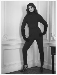 Model Alaina Rae in a dark turtleneck and trousers posing against a panelled wall for Alaïa Lignes d'Hiver