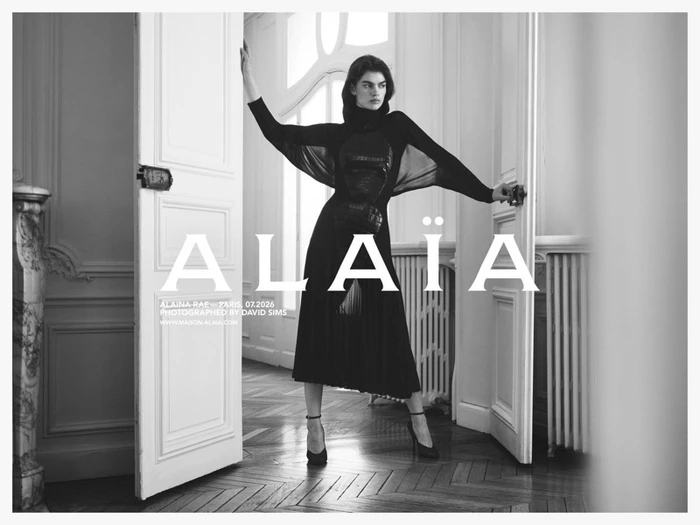 Model Alaina Rae posing in a black dress while opening double doors in a classic interior for Alaïa photographed by David Sims.