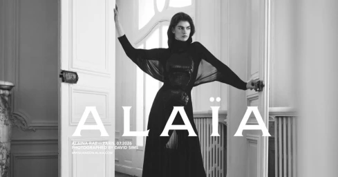 Model Alaina Rae posing in a black dress between open double doors for Alaïa photographed by David Sims