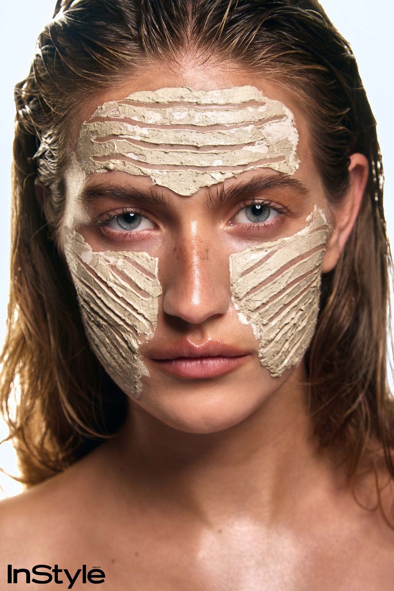Close-up portrait of a woman with wet hair wearing a textured clay face mask, shot by Evangelos Rodoulis for InStyle Greece.