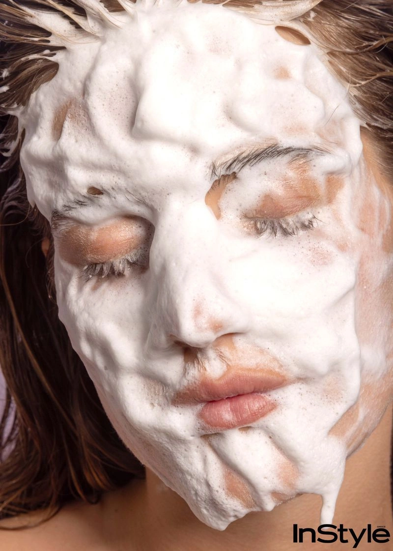 Close-up portrait of a woman with white cleansing foam covering her face, eyes closed, photographed by Evangelos Rodoulis for InStyle Greece