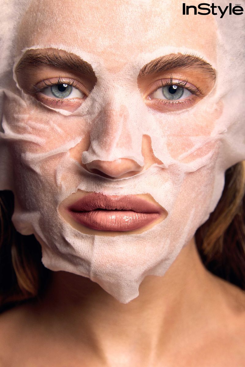 Close-up portrait of a woman wearing a white sheet face mask for skincare, photographed by Evangelos Rodoulis for InStyle Greece.