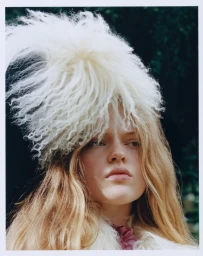 Model Ava Shipp wearing a large textured white furry hat in an editorial portrait by Agata Serge for Revolve.