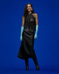 Model in black leather halter dress and blue gloves against a saturated blue studio background for Scanlan Theodore