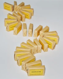 A winding arrangement of brown paper-wrapped rectangular packages with yellow labels featuring the brand name Madeleine.