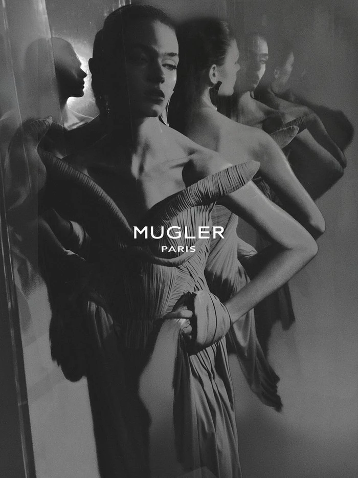 Monochrome fashion campaign image featuring models in structured gowns reflected against mirrored surfaces for Mugler