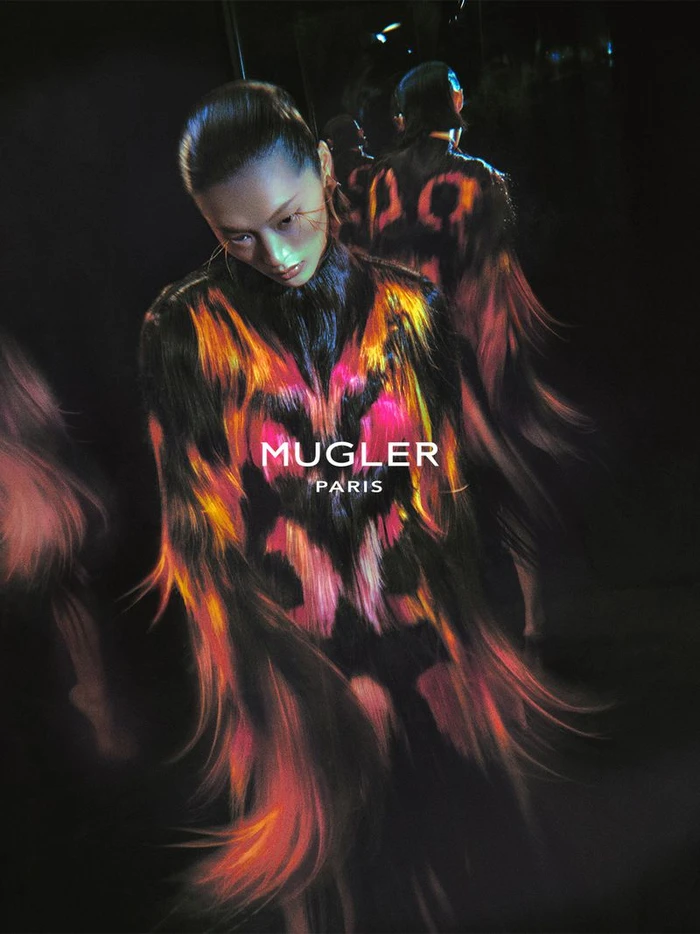 Model in a fiery patterned garment under dramatic dark lighting for Mugler