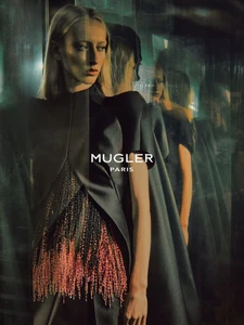 Model wearing dark structured attire with fringing, reflected multiple times in glass against a dark background