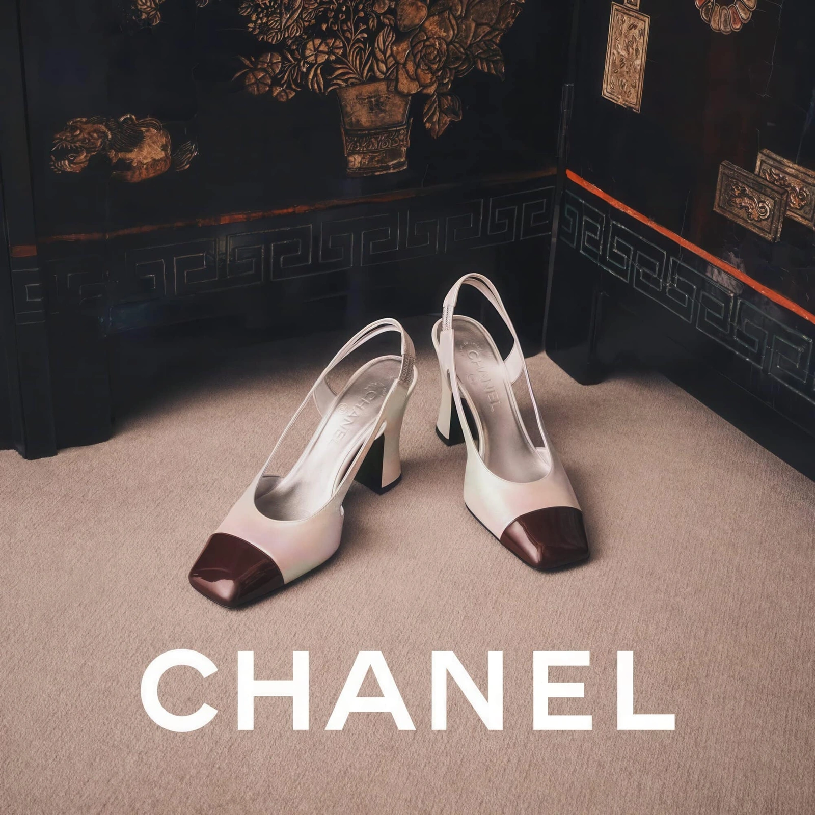 Two-tone slingback heels with dark brown cap toes displayed on carpet before an ornate black lacquered cabinet