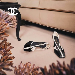 Two-tone black and white slingback heels resting on a beige carpet near a couch and dark wooden table