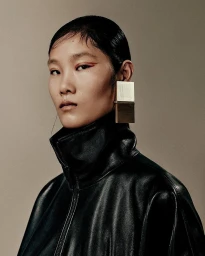 Model wearing a black leather jacket and large metallic earrings for Acne Studios F/W 25 lookbook