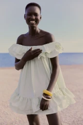 Model Nyakong Chan wearing an off-the-shoulder pale green dress on a sandy beach for H&M Resort Essentials
