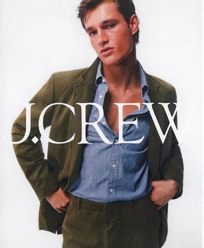 Male model in an olive green suit and unbuttoned blue shirt against a white background for J. Crew