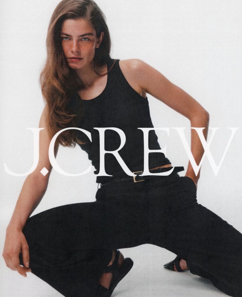 Model wearing a black tank top and dark pants squatting against a plain white background with bold J.Crew text overlay.