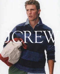 Young man in a striped blue polo shirt holding a canvas and red bag against a white background for J. Crew by Dudi Hasson