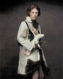 Hunter Schafer in a textured white coat holding crafted toy rats and a black handbag against a dark backdrop for Elle U.S.