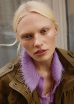 Close-up portrait of blonde model Vilma Sjöberg wearing an olive jacket with a fluffy purple collar for Elle Sweden