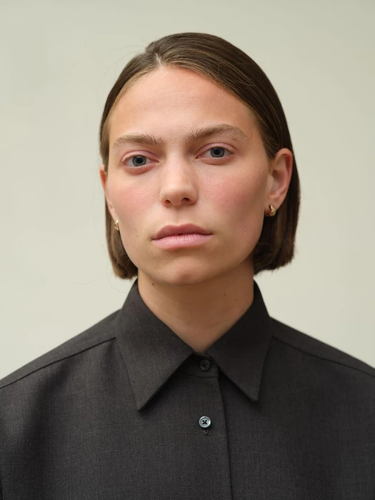 Portrait of a person with short brown hair wearing a dark grey button-down shirt against a neutral background.