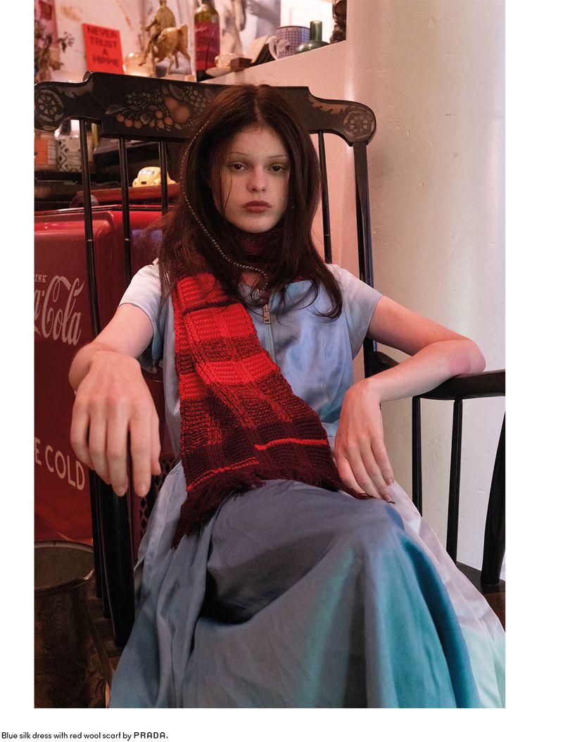 Model Scarlett White seated in a wooden chair wearing a light blue dress and a red scarf for Beyond Noise Issue 6.