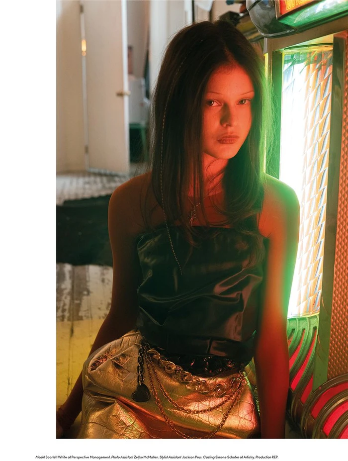 Model Scarlett White sitting next to a glowing green and orange jukebox in an editorial portrait for Beyond Noise.