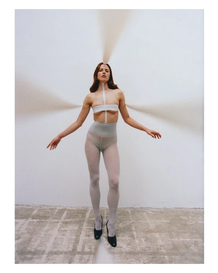 Model Julia Banas in white tights and taped top with streams of sand radiating out for Middle Plane Issue 13