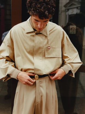 Model Francisco Henriques wearing a beige shirt and trousers adjusting a belt for Z Magazine