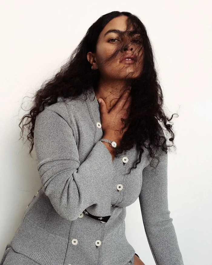Model Ylang Messenguiral wearing a grey knit cardigan with white buttons against a plain white background for M Le magazine du Monde.