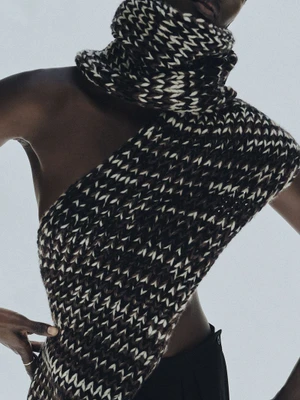 Model wearing a chunky patterned knit scarf and top against a light background for Kallmeyer