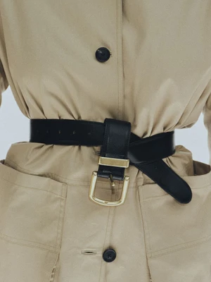 Close-up of a beige coat cinched with a wide black leather belt featuring a gold buckle, from Kallmeyer.