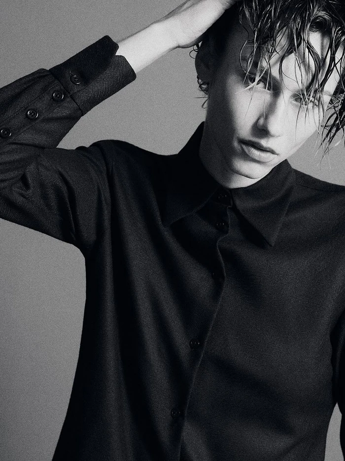 Model with wet hair wearing a black long-sleeve button-up shirt against a plain grey backdrop.