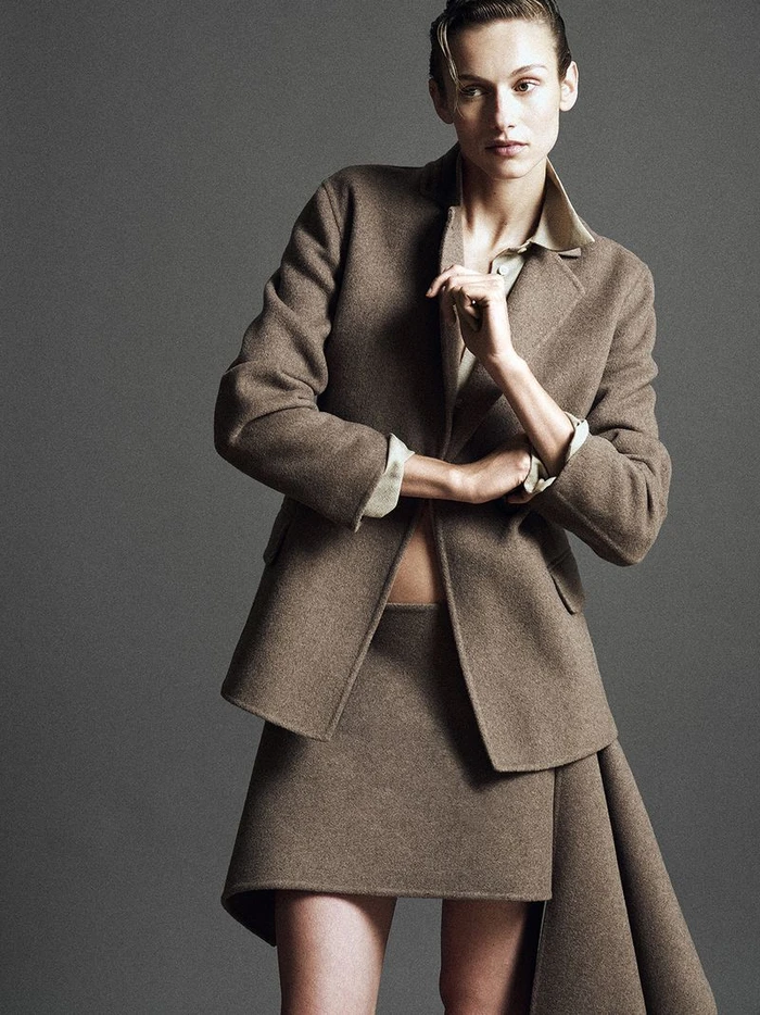 Model wearing a structured brown wool blazer and matching skirt against a grey background for Kallmeyer.