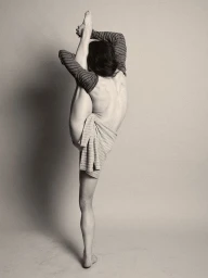 Model in a vertical standing split wearing striped sleeves against a neutral grey studio backdrop
