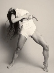 Woman arching backward in a dynamic pose, wearing a white top and shorts against a neutral studio backdrop