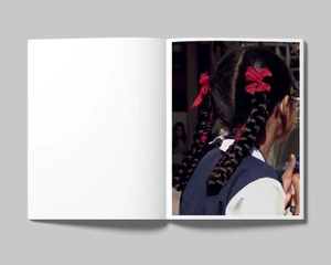 Close-up photograph of a young girl with braided hair tied with red ribbons, shown in an open magazine spread.