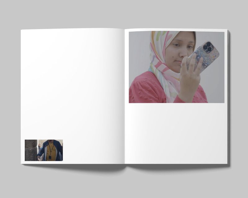 Open magazine showing a woman in a pink top and patterned headscarf holding a smartphone