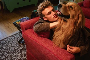 Thijs Leushuis embracing a golden retriever on a red couch for Family Style by Bruce Weber