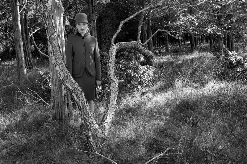 Black and white portrait of Ever Gabo Anderson wearing a tailored jacket and matching hat in a wooded forest setting.
