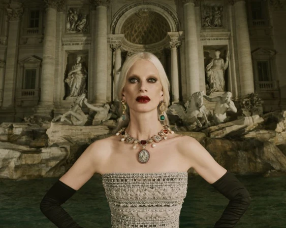 Fashion shot of woman in strapless gown and jewelry standing in front of the Trevi Fountain in Rome, Italy, wearing black gloves.